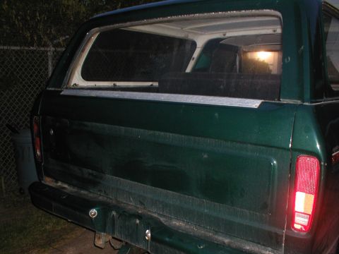 1979 Ford Bronco - The rear of a green SUV is shown, with a close-up of the tailgate and taillight assembly.