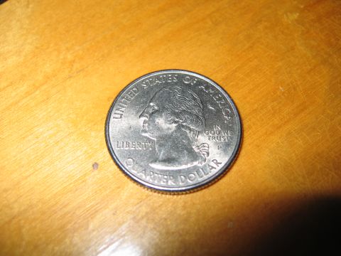 1996 Ford Crown Victoria - A close-up view of a United States quarter dollar coin rests on a wooden surface.