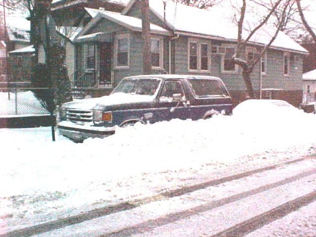 Blue SUV buried in snow, front grille visible