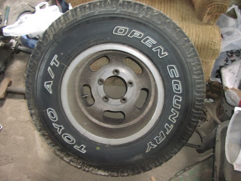 1988 Ford Bronco - A close-up view of a Toyo Open Country A/T tire mounted on a silver wheel, with visible text on the tire sidewall.