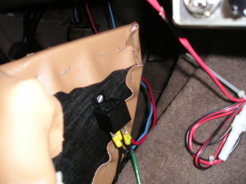 1996 Ford Bronco - Close-up of an automotive relay and its wiring harness, connected to a tan interior panel.