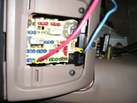 1996 Ford Bronco - Close-up of a vehicle's interior fuse box with visible wiring and a brake release lever.