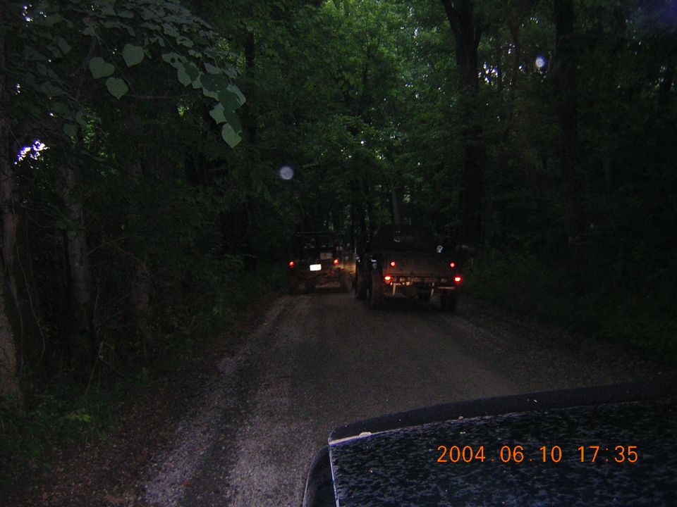 Rear view of two trucks on a dirt road at dusk