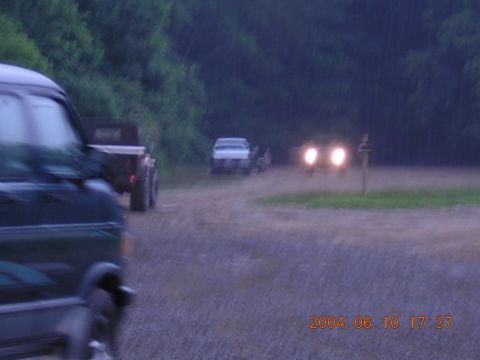1984 Chevrolet Blazer - Multiple vehicles are visible on a dirt road in a wooded area, with headlights illuminating the scene.