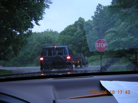1984 Chevrolet Blazer - A dark SUV and trailer are visible through a rain-streaked windshield on a cloudy day.