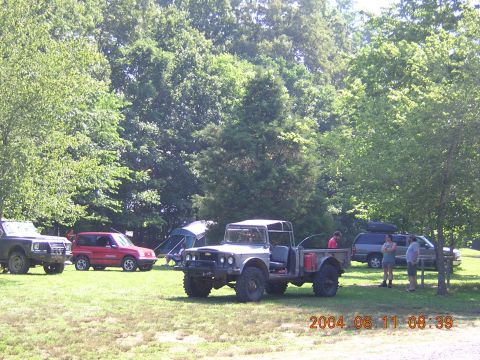 1984 Chevrolet Blazer - A group of off-road vehicles and camping tents are gathered in a park-like setting on a sunny day.