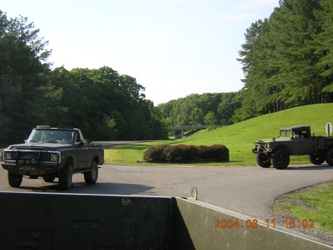 1984 Chevrolet Blazer - Two military trucks are parked on a road with a bridge in the distance.