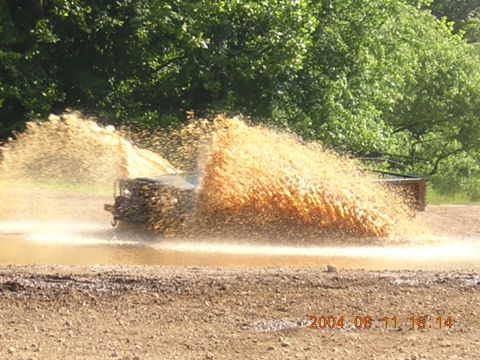 1984 Chevrolet Blazer - A vehicle navigates a muddy obstacle, creating a large splash.