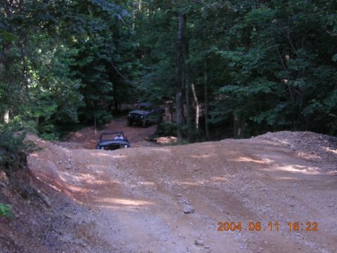 1984 Chevrolet Blazer - Multiple off-road vehicles navigate a challenging dirt track surrounded by dense forest.