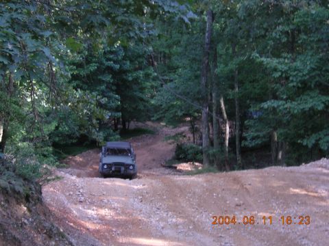 1984 Chevrolet Blazer - A green SUV navigates a rough dirt road through a dense forest.