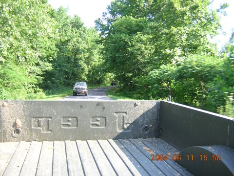 1984 Chevrolet Blazer - View from the bed of a pickup truck shows a 1984 Chevrolet Blazer driving on a road with another vehicle behind it.
