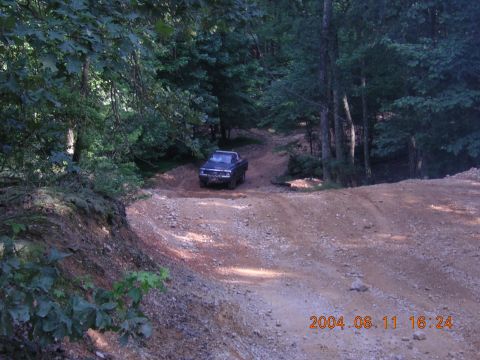 1984 Chevrolet Blazer - A pickup truck navigates a rough dirt path surrounded by trees.