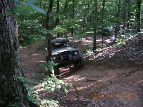 1984 Chevrolet Blazer - An off-road vehicle navigates a wooded trail, with another vehicle visible in the background.