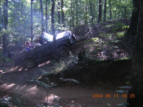 1984 Chevrolet Blazer - A group of people are off-roading in a wooded area on a sunny day.