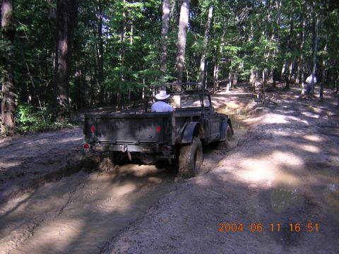 1984 Chevrolet Blazer - A dark, open-top vehicle struggles through a muddy path in a wooded area, with a timestamp indicating it was taken in 2004.