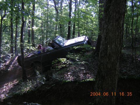 1984 Chevrolet Blazer - A dark SUV navigates a steep, wooded trail with two occupants visible.