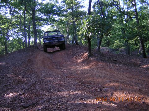 1984 Chevrolet Blazer - Off-road vehicle navigating a steep, rocky dirt trail surrounded by trees.