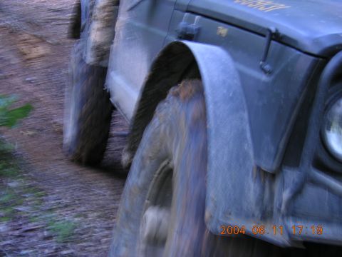 1984 Chevrolet Blazer - This off-road vehicle's front fender and wheel are covered in mud as it drives on a dirt path.