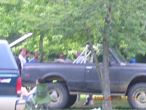 1984 Chevrolet Blazer - People gathered around a dark SUV in an outdoor setting, with another vehicle nearby.