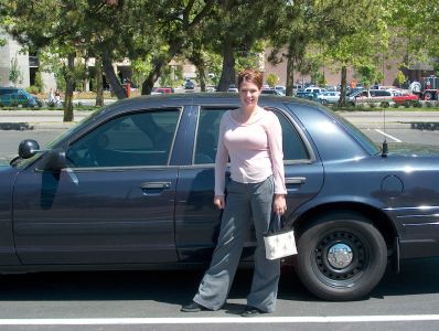 2001 Ford Crown Victoria - A woman poses next to a dark blue sedan in a parking lot.