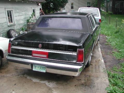 1987 Lincoln Town Car - A black Lincoln sedan is parked on a concrete driveway next to a white van.