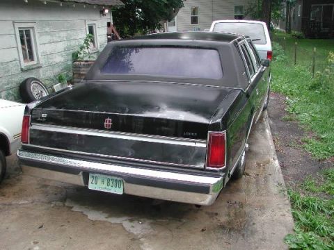 1987 Lincoln Town Car - Rear view of a black 1987 Lincoln Town Car parked next to a white van.