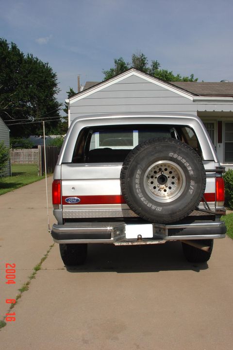 1987 Ford Bronco - Rear view of a silver 1987 Ford Bronco, a red stripe and a spare tire mounted on the tailgate.