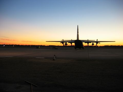1988 Ford Bronco - An airplane is silhouetted against a colorful sunset sky on an airport tarmac.