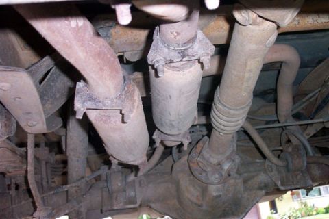 1995 Ford Bronco - View underneath the truck showing two grime-coated cylindrical catalytic converters mounted side by side in the exhaust with band clamps, n…