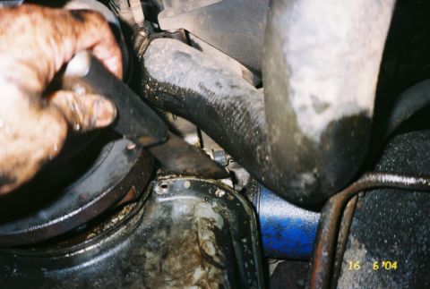 1988 Ford Bronco - A hand is shown working on an engine component, with visible oil and hoses.