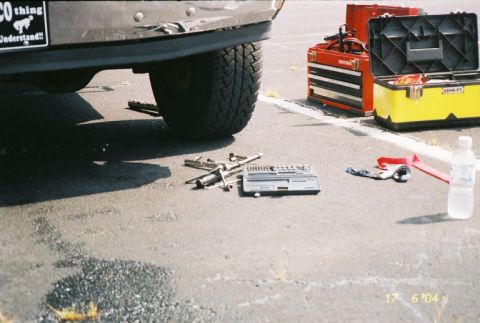 1988 Ford Bronco - Tools are laid out on the ground next to the rear tire of a vehicle.