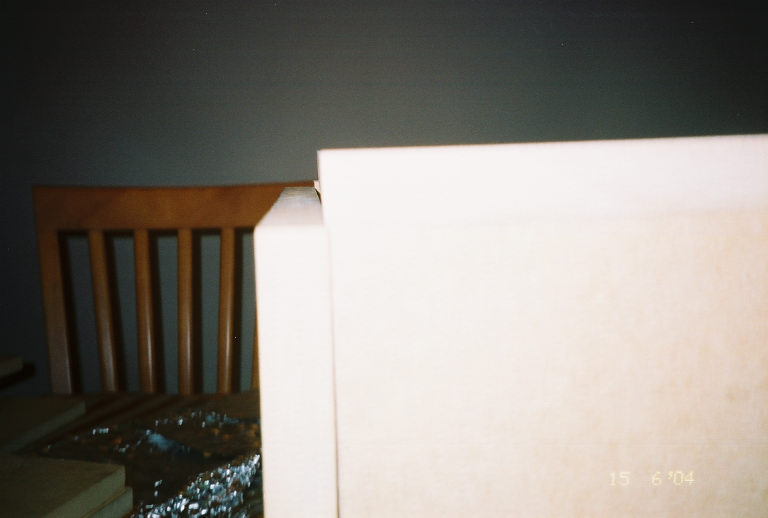 Part of a wooden chair and a white surface in a room. Supermotors logo at bottom right
