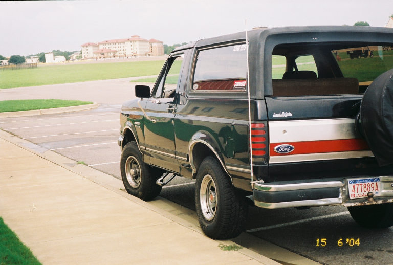 Ford Bronco parked on curb, rear view. Red and white stripe on tailgate