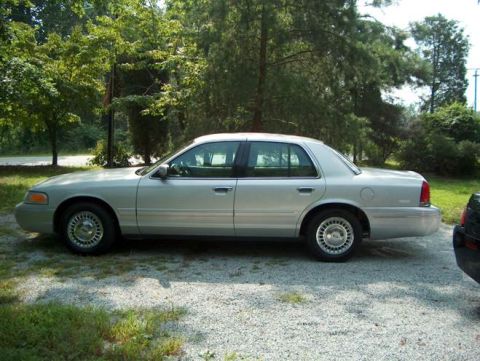 2000 Ford Crown Victoria - Side view of a silver 2000 Ford Crown Victoria parked outdoors on a gravel surface.