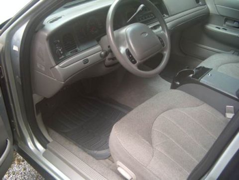 2000 Ford Crown Victoria - The interior of a car is shown, cloth seats, a dashboard, and a steering wheel.