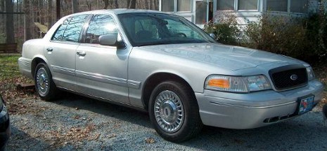 2000 Ford Crown Victoria - This 2000 Ford Crown Victoria is parked outside a building with trees in the background.