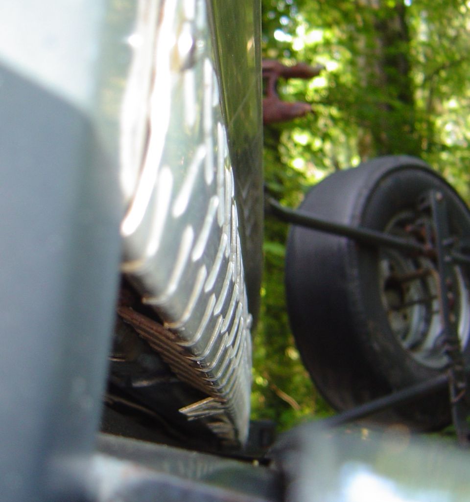 Close-up of diamond-plate aluminum panel on a truck with a bald tire in the background