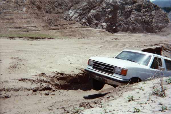 White full-size Ford Bronco descending into a sandy washout off-road