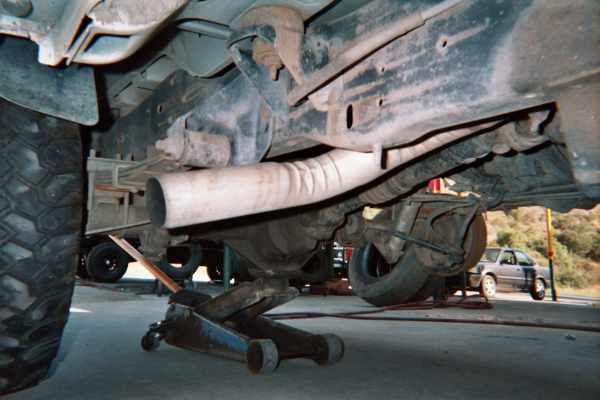 Underside of a vehicle on a floor jack showing exhaust muffler and frame
