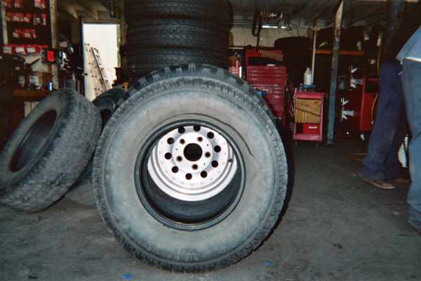 Large off-road tires on white wheels standing inside a garage shop