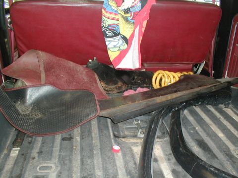 1979 Ford Bronco II - The cargo area of a vehicle contains disassembled parts and a colorful blanket draped over the seats.