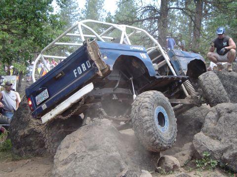 1989 Ford Bronco - A heavily modified blue 1989 Ford Bronco navigates a rocky obstacle course during an event.