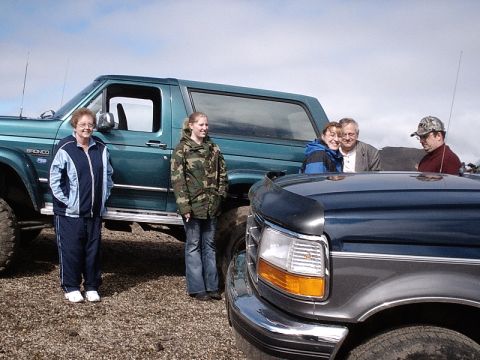 1996 Ford Bronco - A 1996 Ford Bronco and another Ford truck are parked outside with four people.