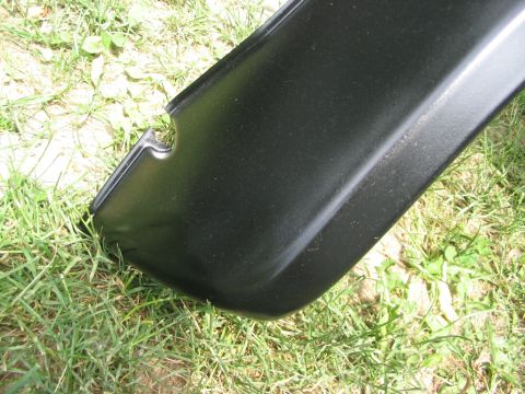 1986 Ford Bronco - A black fender flare with a distinct cut-out rests on a grassy surface.