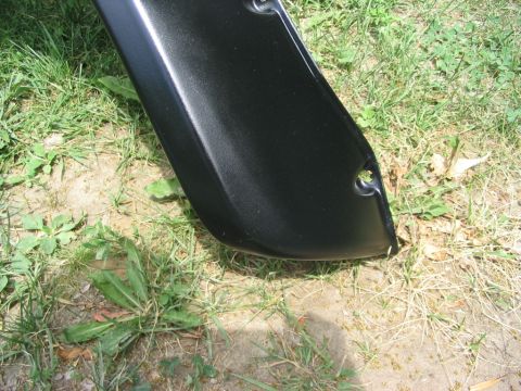 1986 Ford Bronco - A black fender flare is shown close-up, resting on grass and dirt. The "Supermotors.net" watermark is visible in the lower right corner.