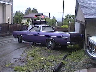 1968 Ford Ranchero - A purple pickup truck is being towed into a garage, with a tow truck visible in the background.