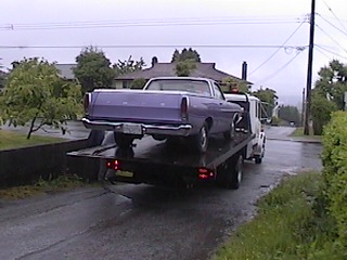 1968 Ford Ranchero - A purple 1968 Ford Ranchero is loaded onto a tow truck on a cloudy day.