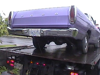 1968 Ford Ranchero - A purple Ford pickup truck is being towed on a flatbed truck.