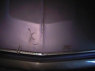 1968 Ford Ranchero - Close-up of a hood emblem on a dark-colored vehicle, with visible damage and a SuperMotors.net watermark.