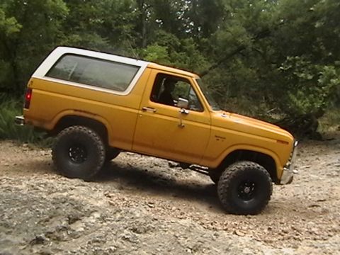 1986 Ford Bronco - Yellow 1986 Ford Bronco navigates a rocky, off-road path.